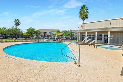 A swimming pool with a metal ladder and a building in the background.